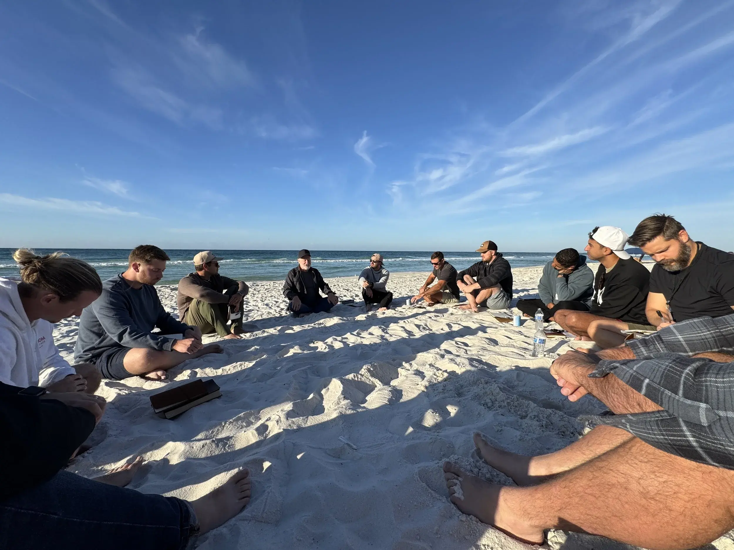 Members sitting in a circle on the beach