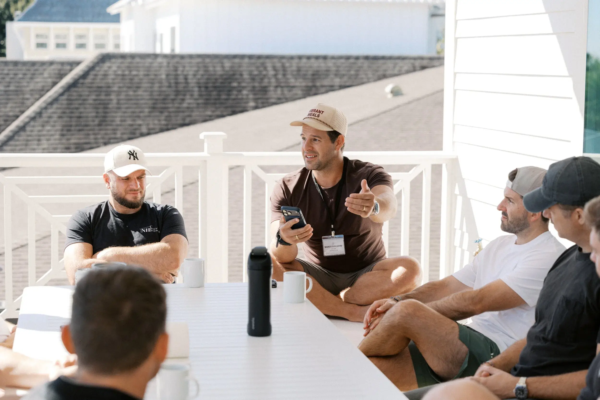 Members in conversation around a table on a porch at the 2025 retreat